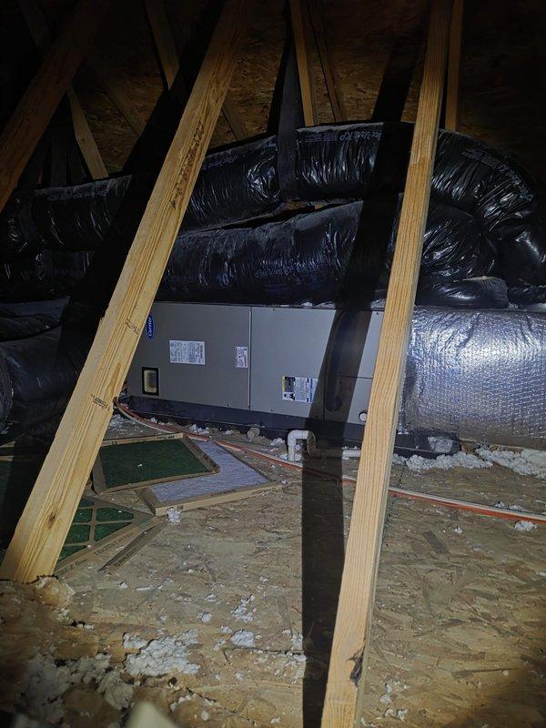 Conducted comprehensive assessment of existing residential HVAC system for replacement estimate. Evaluated outdoor air conditioning condenser unit positioned on gravel pad against home's exterior, noting current installation configuration with electrical conduit and weatherproof disconnect box. Inspected attic-mounted air handling unit and associated ductwork system, including black-wrapped supply ducts and flexible branch runs. Documented equipment specifications, installation conditions, and accessibility factors. Captured detailed photographic documentation of both outdoor condensing unit and indoor air handler locations to support equipment replacement proposal and ensure accurate system sizing recommendations.