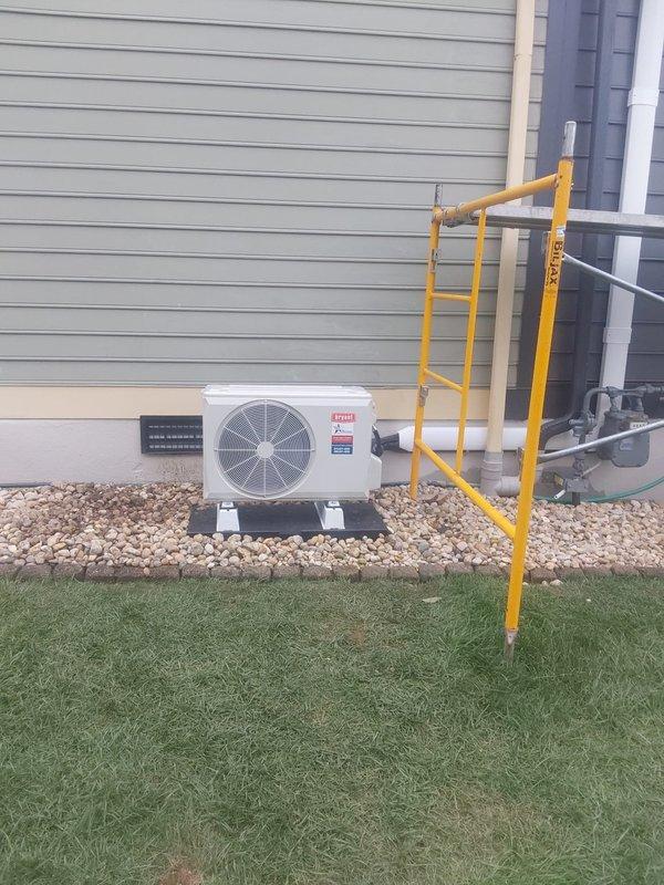 Completed full installation of 9,000 BTU single-zone ductless mini-split system consisting of model 37MAHAQ09AA3 outdoor condenser unit and model D5MAHAQ09XA3 indoor high-wall air handler. Mounted indoor head unit on interior wall above existing computer workspace. Installed outdoor condenser on new concrete pad with snowline block elevation for winter drainage, positioned adjacent to gas meter on west side of property. Ran new copper lineset following existing downspout routing with line hide covering for aesthetic protection. Installed new electrical disconnect box with appropriate fuses and ran high-voltage wiring from main electrical panel to outdoor unit. Ran communication wiring and condensate drain line alongside lineset to complete system connections. All components tested and system operational upon completion.