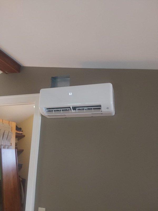 Completed full installation of 9,000 BTU single-zone ductless mini-split system consisting of model 37MAHAQ09AA3 outdoor condenser unit and model D5MAHAQ09XA3 indoor high-wall air handler. Mounted indoor head unit on interior wall above existing computer workspace. Installed outdoor condenser on new concrete pad with snowline block elevation for winter drainage, positioned adjacent to gas meter on west side of property. Ran new copper lineset following existing downspout routing with line hide covering for aesthetic protection. Installed new electrical disconnect box with appropriate fuses and ran high-voltage wiring from main electrical panel to outdoor unit. Ran communication wiring and condensate drain line alongside lineset to complete system connections. All components tested and system operational upon completion.