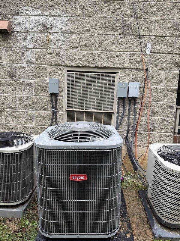 Completed full HVAC system replacement including installation of Bryant 2-ton 15 SEER air conditioning unit (model GA4SAN52400) utilizing R454B refrigerant and Bryant air handler (model FJ5ANXB24L00) with 8kW heat strip. Relocated condenser unit from previous location to ground-level installation on concrete pad positioned against exterior wall alongside existing HVAC equipment. Fabricated and installed sheet metal ductwork connections to integrate with existing supply and return air distribution system. Installed new refrigerant lineset connecting outdoor condensing unit to indoor air handler, electrical disconnect with whip and fuses for condensing unit power supply, and mounted electrical junction boxes with conduit runs for proper code-compliant wiring. Secured all necessary permits for commercial installation. Properly recovered refrigerant from existing equipment and disposed of old HVAC system components in accordance with EPA regulations. Verified system operation, refrigerant 