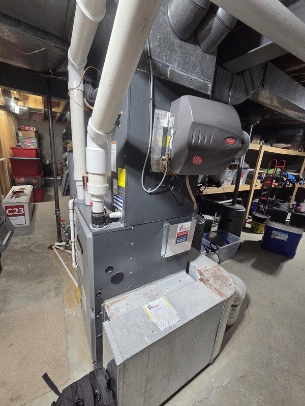 Completed estimate for complete HVAC system replacement in residential basement mechanical room. Evaluated existing furnace, air handler, and humidifier system for replacement, noting current configuration includes gray furnace unit with integrated air handler, mounted humidifier with electronic controls, PVC condensate drainage and venting system, insulated ductwork, and copper refrigerant lines. Documented existing equipment specifications and installation requirements for proposed system upgrade.