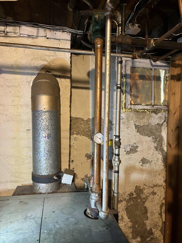 Performed estimate on 58-year-old Weil-McLain gas boiler currently operational but exhibiting age-related wear. Assessed existing heating system including boiler unit, copper piping, pressure gauge, and associated controls in basement mechanical room. Documented equipment condition and discussed replacement options with customer due to advanced age of system.