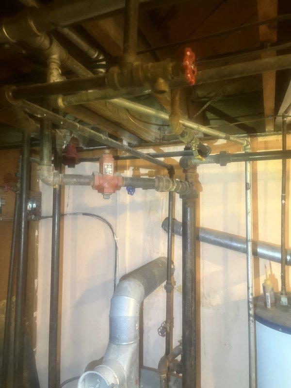 Conducted comprehensive boiler system evaluation in mechanical room. Inspected existing hydronic heating infrastructure including copper supply and return piping with insulation, multiple zone valves, gate valves, and circulator pump assembly housed in blue cabinet enclosure. Assessed piping configuration, valve operation, and overall system condition to provide replacement estimate for aging boiler equipment.