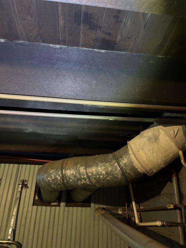 Performed an on-site evaluation for additional HVAC work following a recently completed system installation, documenting existing conditions for a replacement estimate. Inspected the galvanized spiral ductwork and branch connections, noting worn, frayed duct insulation wrap, along with adjacent refrigerant and condensate piping in the mechanical space. Also assessed the electrical service, including the meter socket, conduit, and sub-panel enclosure, to verify power supply conditions for the proposed equipment, with no significant damage observed.