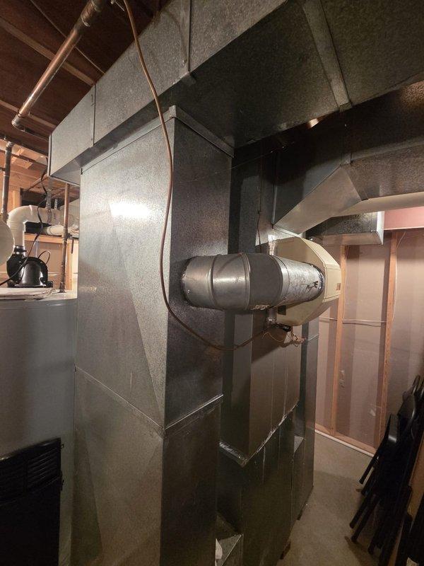 Conducted an on-site estimate for furnace replacement, inspecting the existing thermostat wiring at the terminal block (C, W, Y, RH/RC, G configuration) and evaluating the basement mechanical area, including the supply trunk, ductwork connections, and damper/fan housing. Ductwork and surrounding components showed no major damage, rust, or frost, and the system layout was documented for replacement equipment sizing and installation planning.