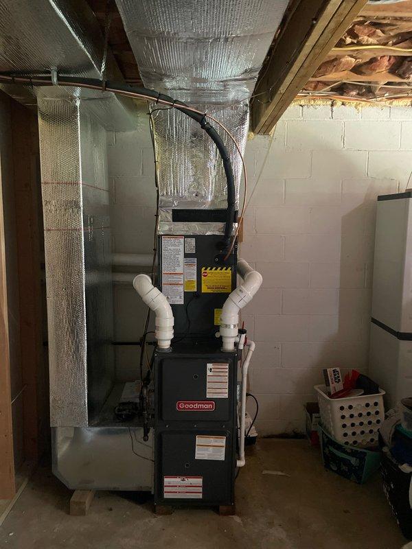 Completed full HVAC system installation including Goodman furnace unit in basement mechanical room and outdoor condensing unit on rooftop. Installed copper refrigerant line set with proper insulation running from rooftop equipment to indoor unit, secured linesets with appropriate bends and routing through gravel pad on roof surface. Mounted furnace with proper clearances from walls, connected white PVC condensate drain lines and black supply ductwork to unit, verified all manufacturer labels and safety placards visible and intact for future reference.
