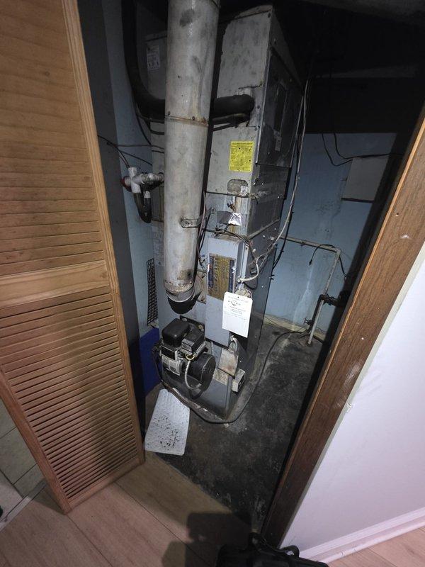 Completed comfort call inspection of residential HVAC system located in basement utility closet. Documented existing furnace unit and associated ductwork, plumbing, and electrical connections through photographic assessment. Equipment shows normal operational wear with dust accumulation on surfaces and components, consistent with standard residential use requiring routine maintenance attention.