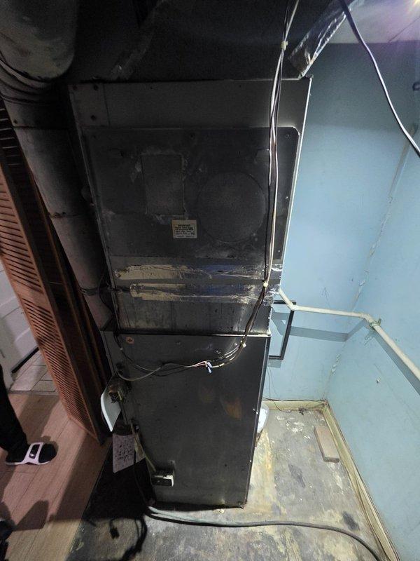 Completed comfort call inspection of residential HVAC system located in basement utility closet. Documented existing furnace unit and associated ductwork, plumbing, and electrical connections through photographic assessment. Equipment shows normal operational wear with dust accumulation on surfaces and components, consistent with standard residential use requiring routine maintenance attention.