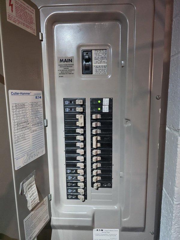 Completed comfort call inspection of residential HVAC system. Documented electrical service panel showing Cutler-Hammer/Eaton 150-amp main breaker with dual columns of circuit breakers in proper operating condition. Panel exhibited clean, well-maintained condition with no visible corrosion or damage. Inspected outdoor Lennox air conditioning condenser unit installed on concrete pad with proper electrical disconnect and conduit installation. Unit positioned against brick exterior with adequate clearance and proper landscaping maintenance around equipment.