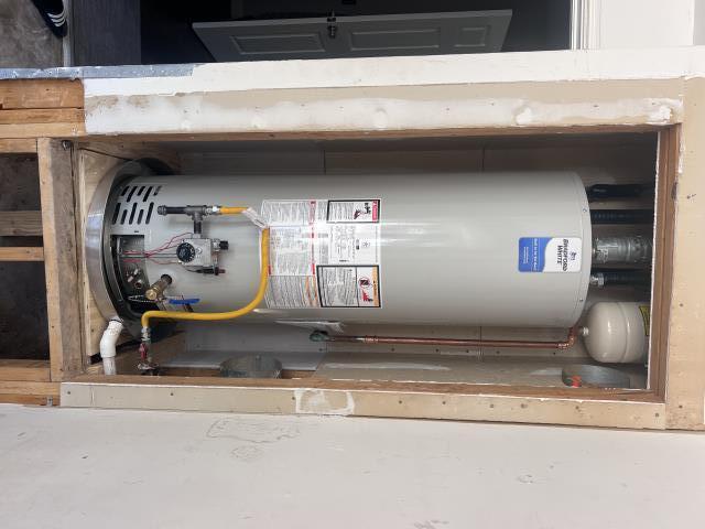 Water heater installation showing a Bradford White tank with gas connections, shut-off valve, and plumbing details in a residential setting, relevant to American Eagle Plumbing services.