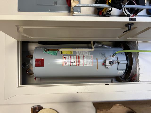Rheem 50-gallon tank-style propane water heater installed in a utility closet, showcasing plumbing connections and safety labels, relevant to American Eagle Plumbing's services in Lakeway, TX.