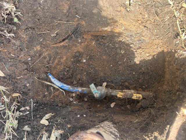 Supply and install new pressure reducing valve and 2 gallon expansion tank to match new water pressure. Outdoor plumbing installation showing a buried spigot with blue pipe and valve in soil, relevant to American Eagle Plumbing's services in Pflugerville, TX.