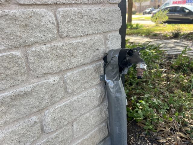 Supply and install new outdoor spigot with a code approved vacuum breaker. Remove ans dispose of the old spigot. Outdoor spigot with duct tape repair on brick wall, highlighting plumbing fixture maintenance and installation services by American Eagle Plumbing in Pflugerville, TX.
