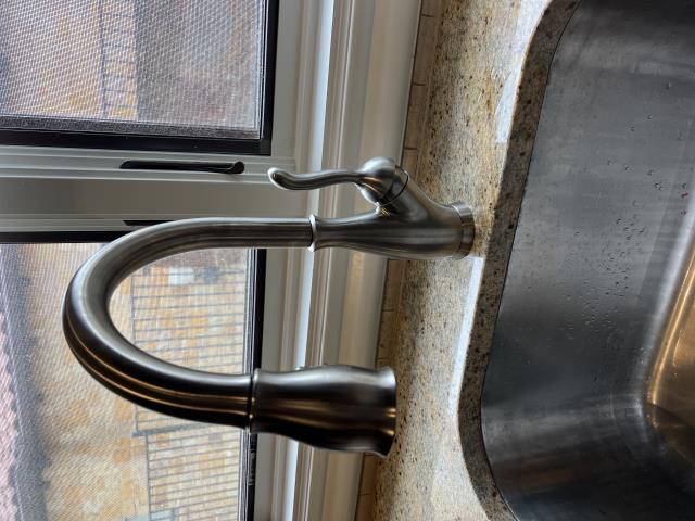 New delta laundry faucet installed in a modern kitchen setting with a stainless steel sink and natural light.