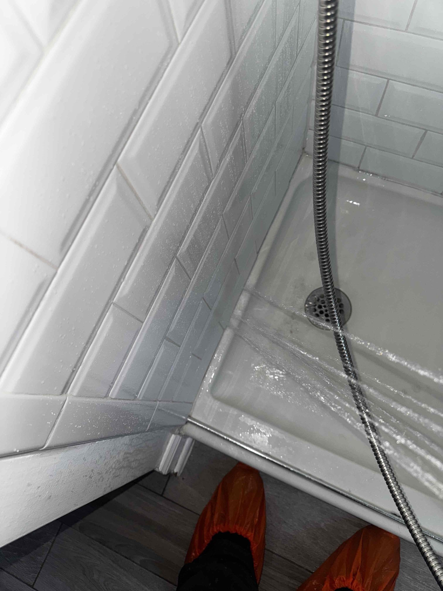 We had recently had replaced the showerhead for the client, we arrived today due to a leak and staining on the ceiling right above the shower. In order to determine if it is related to the showerhead swap out, I disconnected the shower trim to get access and see inside the wall. With the trim removed, I turned on both shower heads and it is completely dry in the wall. I next sprayed water along the seams of the tile and shower base to recreate the problem. I then sprayed the handheld towards the corner of the shower door and wall, and within a matter of 20sec, the whole bathroom floor fills with water. There are many problem spots on the tiling and grout, along with a huge grout line missing in front of the toilet. I also determined that the bathroom group is not very level, reason I know this, is because when I sprayed the corner and water leaks out and onto the floor, the water pitch’s towards the opening. At this time, it appears that the leak is not plumbing related. Without cuttin