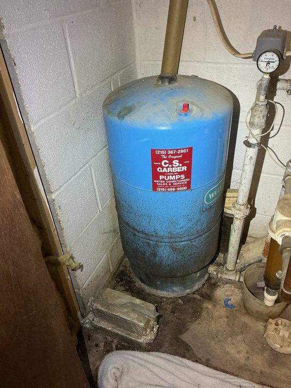 Performed scheduled preventative maintenance on water pressure tank system in basement. Upon inspection, found significant corrosion and mineral buildup on connecting pipes and joints, particularly at connection points. Serviced aging water treatment system, addressing the leaking water storage tank (approximately 20 gallon) which showed considerable discoloration and grime accumulation on the lower section.