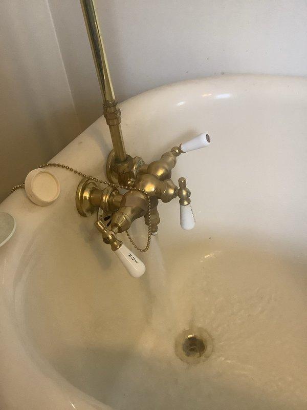 Completed scheduled preventative maintenance service by replacing the brass fixtures on bathtub. Installed new polished brass faucet assembly with hot/cold handles featuring porcelain caps and drain stopper mechanism with pull chain. P-trap drainage system was properly connected and tested for leaks after installation.