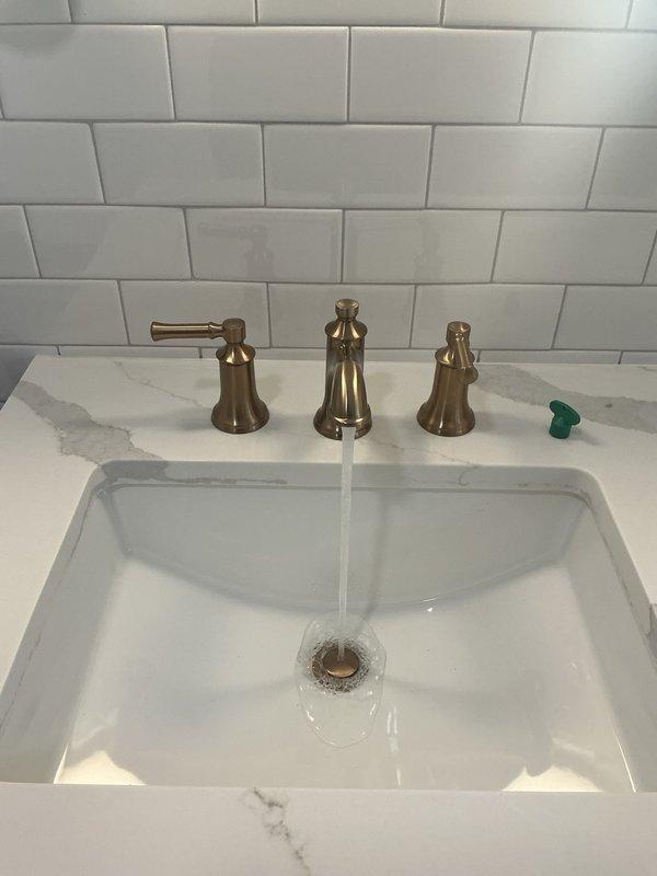 Completed second stage of bathroom remodel by installing and connecting the undermount sink with brushed brass widespread faucet to water supply, installing toilet with proper supply line connection, and finalizing shower installation by adding tub spout, trim plate and handle to previously installed shower valve. All fixtures were tested for proper function and water flow with no leaks observed.