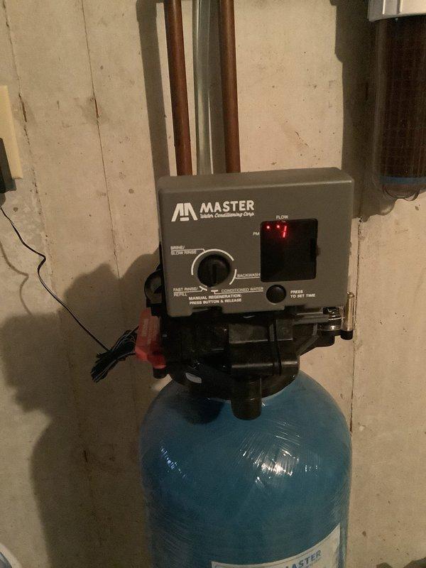 Diagnosed water treatment system with customer complaint of minimal salt consumption and hard water spots. Inspected Master water softener unit which showed illuminated flow indicator light but minimal salt depletion. Examined control valve and electronic components including circuit board with blue cylindrical components and purple indicator light. System appears properly installed but not functioning correctly; customer is monitoring situation with follow-up service potentially required.