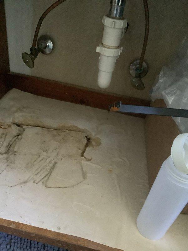 Responded to service call for ceiling leak originating from upstairs shower. Inspection revealed significant water damage and deterioration to the cabinet floor beneath plumbing fixtures, with visible moisture intrusion affecting the surrounding materials. Identified failed shower valve as the source of the leak and scheduled return visit with replacement part to complete the repair.