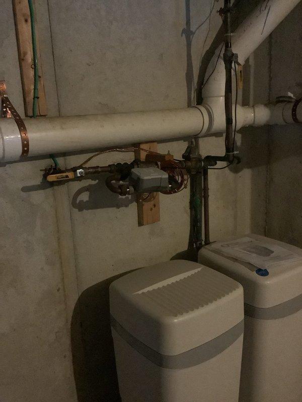 Completed comprehensive plumbing inspection of basement utility area, examining exposed PVC drainage system, copper supply lines, and dual water treatment units. Verified proper installation of pipe mounting brackets, connection integrity at all joints, and functionality of control valve assembly. Inspection was coordinated with heating system evaluation.