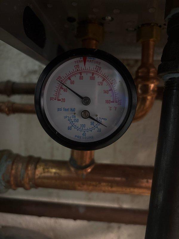 Replaced defective temperature and pressure gauge on Burnham Alta boiler under manufacturer warranty. Isolated boiler system and drained water to access gauge assembly. Removed failed gauge from copper piping and installed new replacement unit with proper fittings. Refilled boiler to correct operating pressure, purged air from system piping, and verified proper operation of new gauge with accurate temperature and pressure readings displayed.