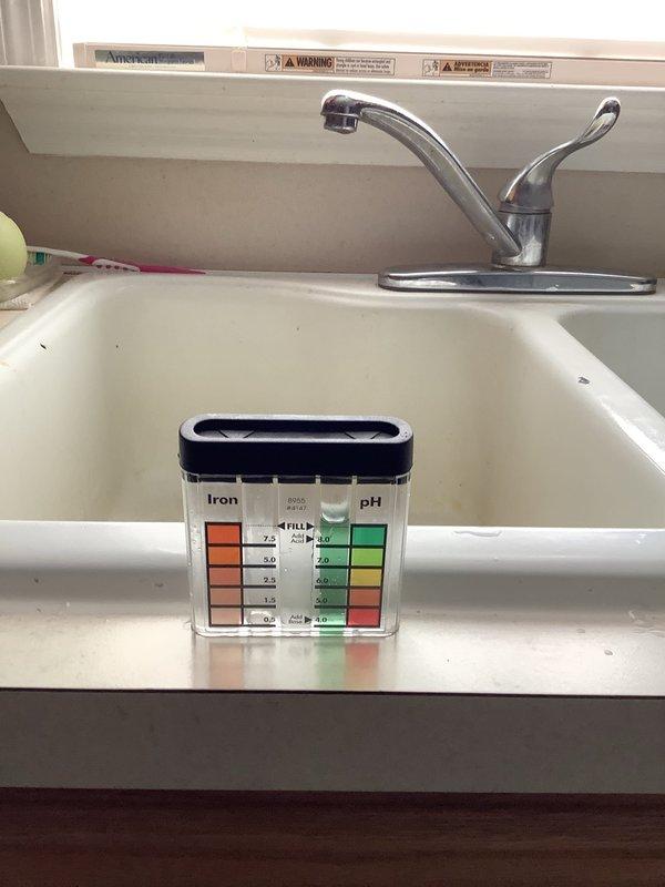 Responded to intermittent water loss affecting all fixtures throughout the residence. Inspected well pump, pressure switch, and water treatment system including Hague water softener and acid neutralizer installed in 2024. Upon examination, discovered acid neutralizer media level unchanged and water softener salt level static for three months, indicating treatment system not cycling properly. Performed raw and treated water quality testing using test strips to analyze iron levels and pH values at kitchen sink location. Utilized multimeter to test electrical components and pressure switch functionality. Conducted comprehensive plumbing system inspection as requested. Water filter housing showed white mineral buildup on exterior, suggesting water chemistry issues. Documented findings with water test results and system condition for customer records.