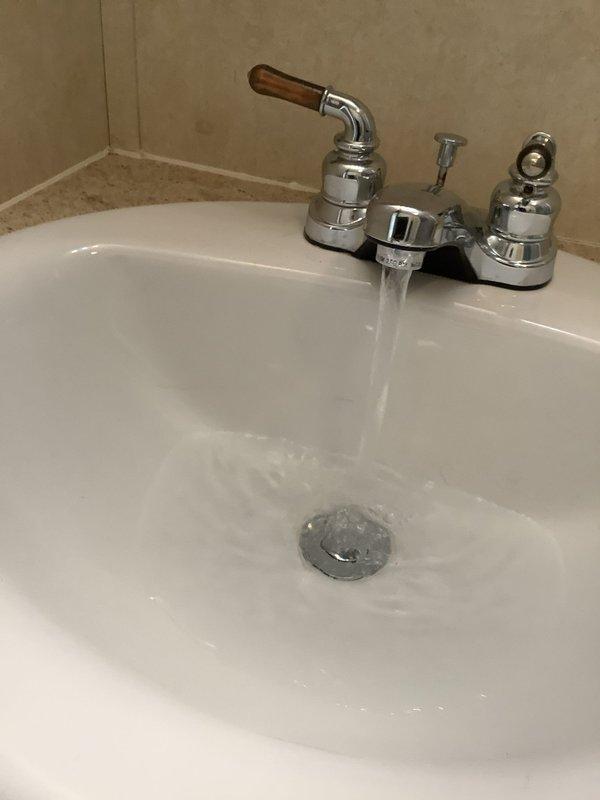 Responded to service call for bathroom sink pop-up drain assembly issue. Upon arrival, inspected existing chrome pop-up drain with gray stopper and two-handle faucet assembly. Assessed whether drain nut could be replaced or if complete pop-up assembly replacement was necessary. Tested drain operation and water flow to determine extent of repair needed. Also evaluated existing Briggs toilet for potential rebuild and provided pricing information for comfort height toilet replacement option per customer request.