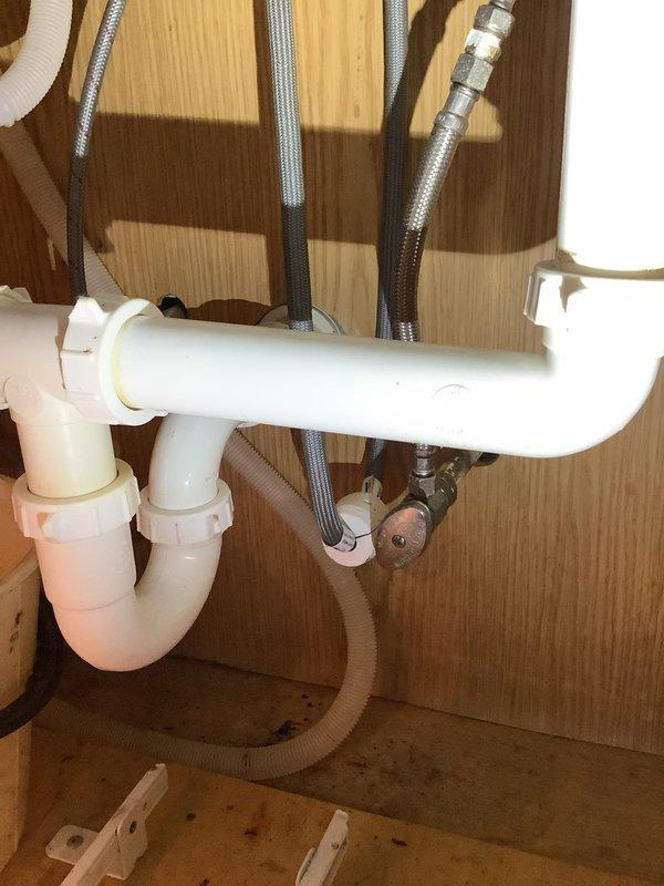 Responded to emergency call for kitchen sink not draining. Disassembled P-trap assembly and drain piping beneath sink to inspect for obstruction. Attempted to clear blockage using drain snake through accessible drain lines. No obstruction located in the visible piping or P-trap. Based on inspection findings, determined that clog is likely located further downstream in the system, either at the vent stack or at the main line in the basement area, requiring additional access points for proper clearing.