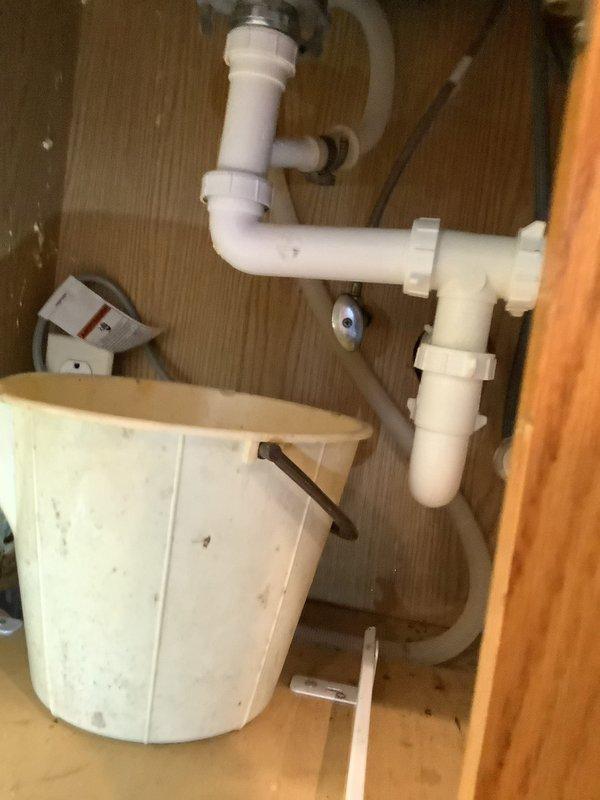 Responded to emergency call for kitchen sink not draining. Disassembled P-trap assembly and drain piping beneath sink to inspect for obstruction. Attempted to clear blockage using drain snake through accessible drain lines. No obstruction located in the visible piping or P-trap. Based on inspection findings, determined that clog is likely located further downstream in the system, either at the vent stack or at the main line in the basement area, requiring additional access points for proper clearing.