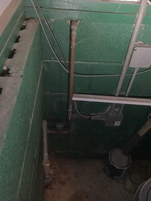 Responded to service call for outdoor faucet at rear of property experiencing leakage and stiff handle operation following winter freeze conditions. Upon inspection, determined that frost damage had compromised the hose bibb assembly, causing internal seal deterioration and stem binding. Accessed supply lines through basement utility area to assess extent of damage and verify proper shutoff capability. Documented existing conditions showing utility piping configuration and access points for future reference. Recommended replacement of freeze-damaged exterior faucet with frost-proof sillcock to prevent recurrence of cold weather failures.