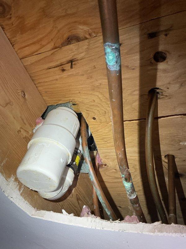 Responded to emergency call for upstairs tub drain leak causing water damage to living room ceiling below. Upon arrival, found significant ceiling deterioration with paint peeling and water pooling behind drywall. Accessed plumbing from above and identified leaking drain trap assembly with corroded copper supply lines showing extensive oxidation. Repaired drain connection, replaced damaged trap components, and verified all connections were secure and leak-free before cleanup.