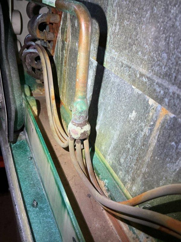 Completed comprehensive tune-up and maintenance service on oil-fired furnace and central air conditioning system, both over 20 years old. Performed thorough cleaning and inspection of oil furnace components, replaced air filter showing significant dust accumulation, and serviced central AC unit. Observed moderate corrosion on copper refrigerant lines with green patina at connection points and oxidation on mounting hardware, indicating age-related wear. Both systems are currently operational but showing signs of aging; provided assessment that equipment may benefit from replacement consideration in near future, with heat pump conversion as potential upgrade option for improved efficiency.