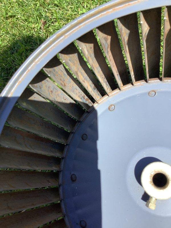 Completed preventive maintenance inspection on air conditioning system. Removed and thoroughly cleaned heavily soiled blower wheel that exhibited significant dirt, dust, and debris accumulation on curved metal blades and blue-painted housing. Cleaned exterior grille louver assembly which showed substantial buildup of environmental contaminants including dust, pollen, and grime across all horizontal slats. System components inspected and reassembled following cleaning procedures.