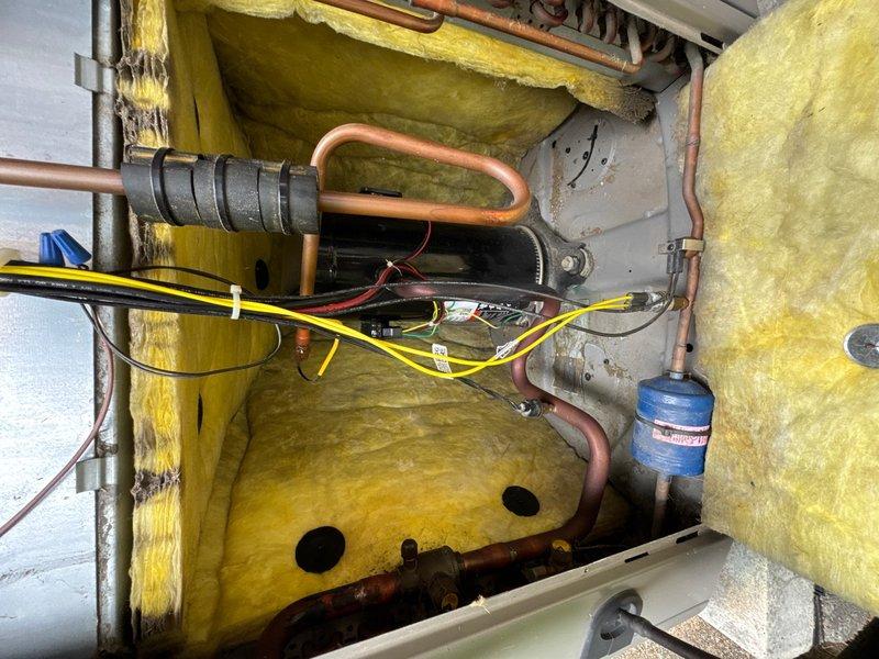 Completed comprehensive preventive maintenance inspection on upstairs air conditioning system. Accessed exterior-mounted condensing unit, removed service panels, and thoroughly inspected all electrical and mechanical components. Verified proper operation of dual control boards, capacitor, and all electrical connections throughout the system. Examined refrigerant line set for proper insulation and signs of wear, noting normal patina on copper tubing consistent with system age. Inspected filter-drier and associated refrigerant piping for corrosion or deterioration. All wiring connections secured and functioning within normal parameters. System components showing typical operational wear with no immediate service needs identified. Unit returned to normal operation following inspection.