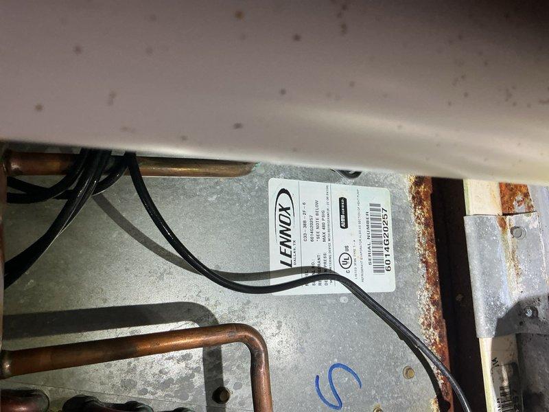 Responded to service call for Lennox air conditioning system not maintaining temperature with indoor unit freezing up in basement. Upon inspection, found evidence of previous refrigerant addition and signs of system age with visible corrosion on components. Diagnosed freezing coil condition, documented electrical connections at outdoor unit and indoor air handler condition with rust present on mounting brackets and housing. System installed approximately 11 years ago with recent filter change completed by occupant prior to service visit.