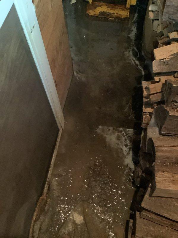 Responded to water leak in basement with standing water on concrete floor. Upon inspection, identified source of water intrusion and assessed damage to surrounding area including wooden floor joists and subflooring. Documented conditions showing significant water accumulation and moisture exposure to structural elements and foundation walls.