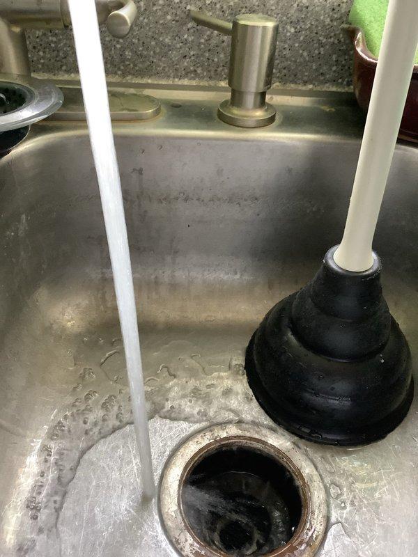 Responded to clogged kitchen sink drain that was initially slow-draining before becoming completely blocked. Customer had disposed of large quantity of rice through garbage disposal, which does not break down and caused the obstruction. Attempted to clear blockage using plunger and chemical drain cleaner without success. Inspected sink basin, drain assembly, and P-trap configuration beneath sink. Due to severity of blockage and unsuccessful initial clearing attempts, additional service scheduling required to properly address obstruction with appropriate equipment and techniques.