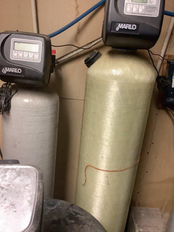 # After Hours Emergency Service

Responded to emergency call for water treatment system malfunction. Upon arrival, found dual-tank Marlo water softening system with control unit displaying error codes. Inspected both fiberglass tanks and associated plumbing connections. Diagnosed control valve failure on primary softener unit causing system to lock out. Reset control head, verified proper operation of brine draw cycle, and tested water flow through both treatment vessels. Checked copper supply lines and blue PVC distribution piping for leaks or restrictions. Confirmed system returned to normal automated regeneration cycle. Verified water quality output and ensured all electrical connections were secure. System restored to full operational status.