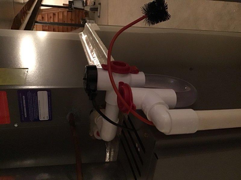 Installed E-Z trap add-on accessory to the existing HVAC condensate drain system. The installation included mounting the trap assembly to the air handler unit using white PVC piping connections and securing all fittings with appropriate caps. Verified proper drainage flow and confirmed the system is operating correctly with the new trap preventing air lock issues in the condensate line.