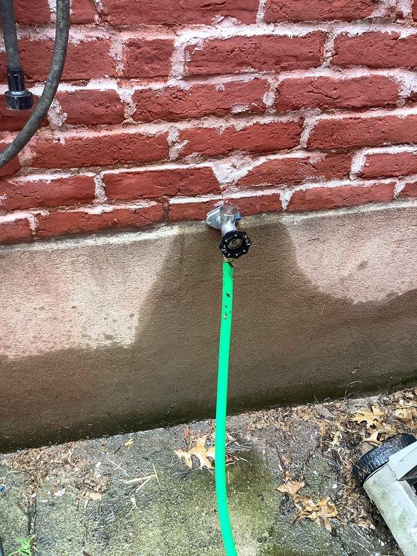 Responded to service call for outdoor hose bib that was not winterized and suspected to have frozen damage. Inspected exterior wall-mounted hydrant fixture at foundation level where brick meets concrete slab. Confirmed freeze damage to spigot assembly from water left in line during winter months. Removed damaged hose bib, replaced with new frost-free sillcock unit, and secured mounting hardware to brick wall. Tested new fixture for proper operation and verified no leaks at connection points.