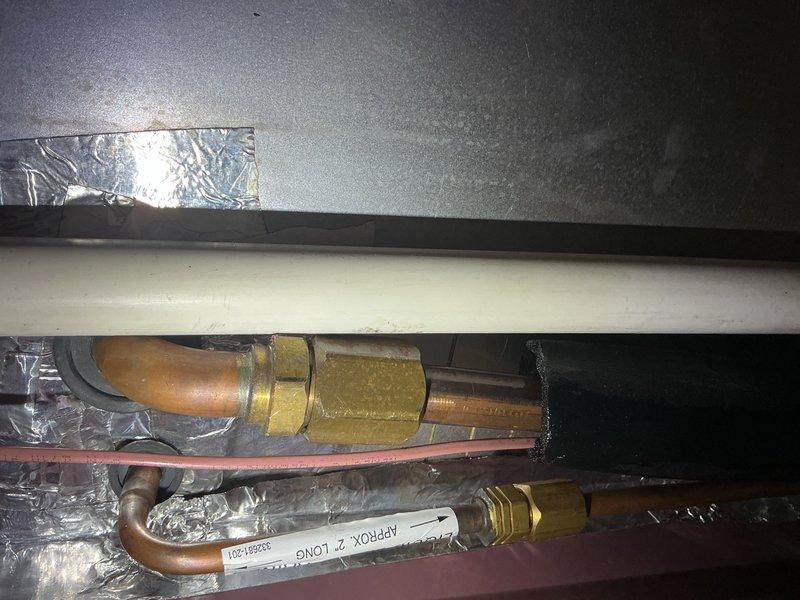 # After Hours Emergency HVAC Service

Responded to an after hours emergency call for HVAC system issues. Upon arrival, accessed the mechanical space and inspected the ductwork assembly and refrigerant line connections. Found compromised insulation and potential refrigerant line concerns in the confined crawlspace area. Documented existing copper piping configuration, brass compression fittings, and condensate drain line routing. Assessed the condition of thermal barriers and metallic insulation wrapping around primary refrigerant lines. Verified all pipe connections and fittings for proper installation and potential leak points. Photographed the installation for service records showing the white insulated refrigerant line, copper tubing with brass fittings, and surrounding ductwork assembly. System components were located in a tight access area with concrete flooring requiring careful navigation. Completed visual inspection of all accessible HVAC components and documented findings for 