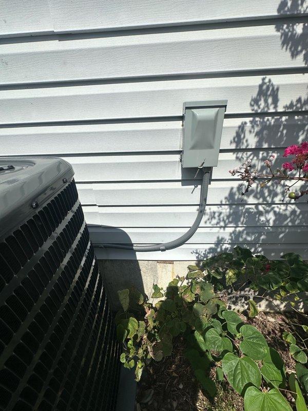 Responded to customer complaint of loud noise from outdoor condensing unit. Upon arrival, inspected exterior AC condenser and electrical components including disconnect box and wiring connections. Unit was operating and producing cold air as reported, though customer noted occasional overcooling issues. Performed visual assessment of condenser unit, electrical disconnect panel, and associated conduit. Documented equipment condition and installation setup with photographs for service records.