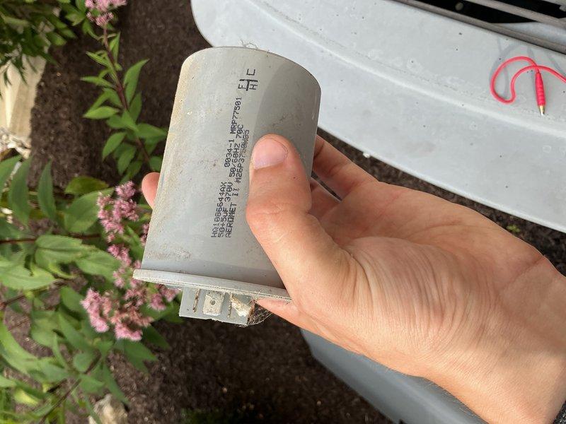 Responded to no cooling call on 25+ year old residential air conditioning system. Found indoor unit fan operating but delivering warm air with outdoor condensing unit completely non-operational. Diagnosed failed run capacitor preventing compressor and outdoor fan motor from starting. Removed defective capacitor and installed replacement unit with proper microfarad rating and voltage specifications. Verified outdoor unit startup, confirmed compressor operation, and tested system performance. Unit cooling properly upon departure.