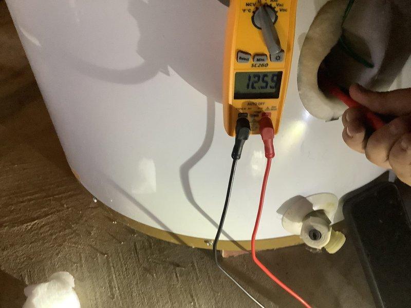 Responded to service call for water heater with reported lower element error. Upon arrival, confirmed unit was producing hot water. Performed diagnostic testing using digital multimeter on lower heating element assembly, obtaining voltage reading of 12.59V. Accessed electrical junction box and inspected wiring connections and wire nuts for proper installation. Documented existing conditions with photographs showing electrical components and testing procedures for service records.