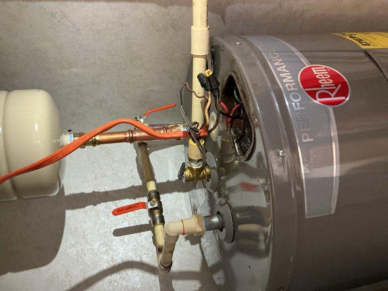 Responded to service call for water heater leaking at top of unit. Upon inspection, identified leak originating from plumbing connections at top of Rheem Performance Platinum electric water heater. Assessed all copper pipe fittings, brass valves, expansion tank connections, and pressure relief valve discharge piping. Tightened loose fittings and verified proper sealing of all connections. Tested system operation and confirmed leak was resolved with no further water discharge observed.