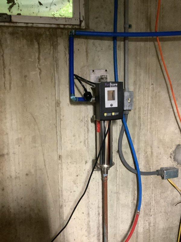 Replaced UV bulb in Purificare Enhanced Disinfection water treatment system mounted in basement utility area. Obtained customer approval prior to installation, completed bulb replacement, and verified system operation with display showing proper functionality.