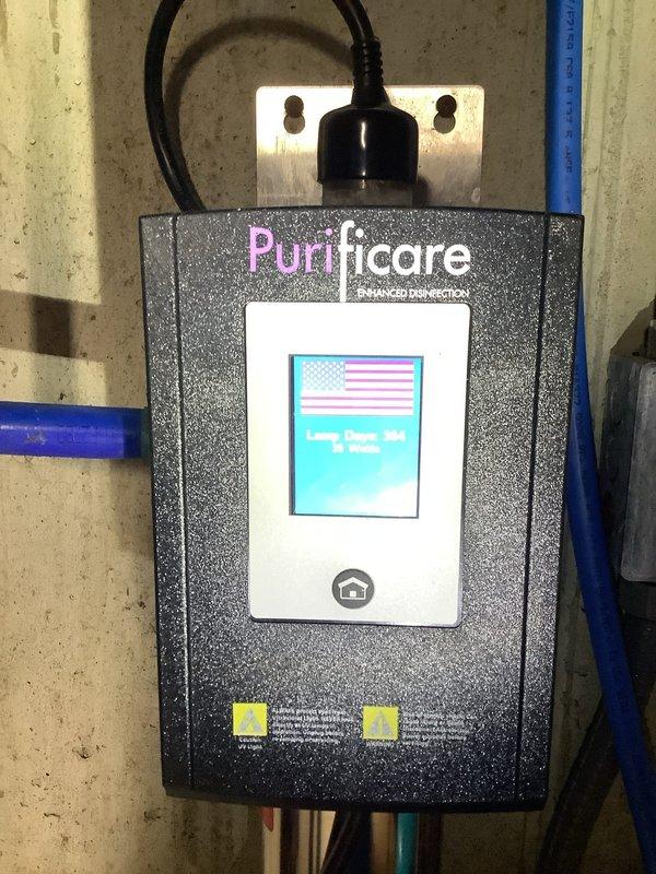 Replaced UV bulb in Purificare Enhanced Disinfection water treatment system mounted in basement utility area. Obtained customer approval prior to installation, completed bulb replacement, and verified system operation with display showing proper functionality.