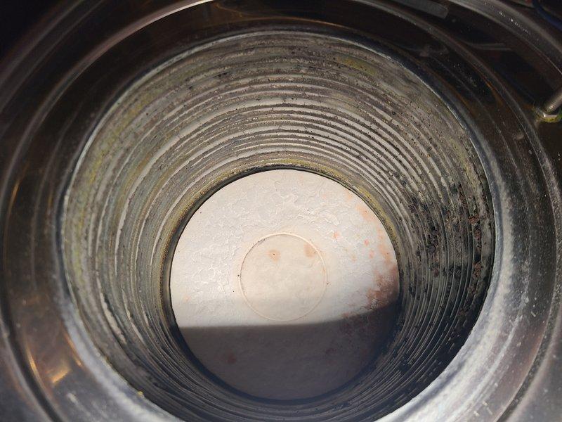 Performed re-check on K-2 combination boiler following previous fan speed adjustment. Inspected burner assembly and heat exchanger components, documenting conditions with photographs showing normal operational wear patterns and minor surface oxidation on internal components. Provided customer education regarding domestic hot water delivery times in relation to fan speed settings and proper system operation expectations for the 2019 natural gas unit.