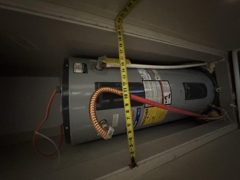 Completed mobile home water heater replacement after initial installation revealed oversized unit for confined space. Returned with properly sized water heater to accommodate tight clearances in utility closet. Installed new water heater with copper flex lines, drain pan, and proper electrical connections in white-painted enclosure with adequate clearance measurements verified.